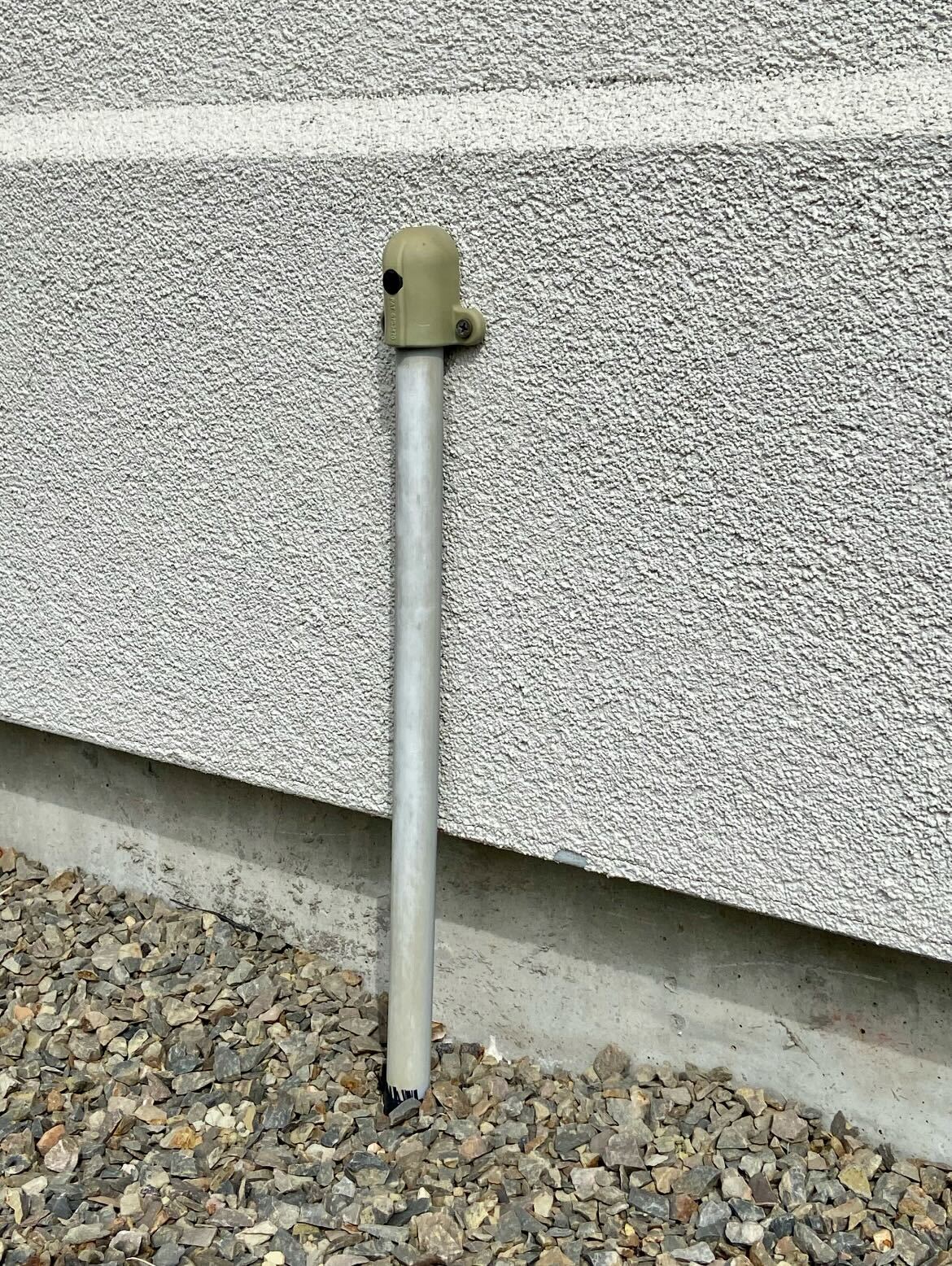 Metal pole next to garden wall and gravel